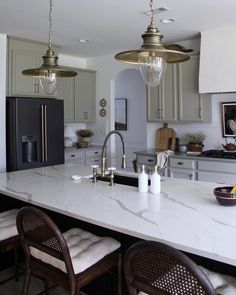 a kitchen with two lights hanging from the ceiling and marble counter tops on the island