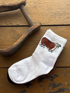 a pair of socks with a brown and white cow on them sitting next to a wooden rocking chair