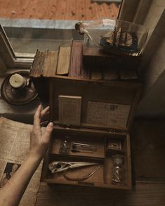 a person reaching for an open book on top of a wooden table next to a window