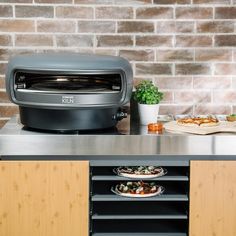 a toaster oven sitting on top of a counter next to pizzas and other food