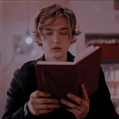 a young man reading a book while sitting down