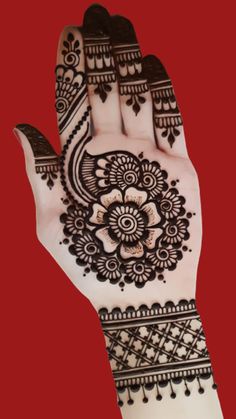 a hand that is decorated with henna and flowers on the palm, against a red background