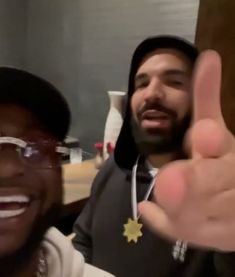 two men giving the thumbs up sign in front of a mirror with one man wearing glasses