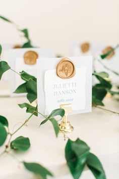 place card holders with gold wax stamp and greenery on the table at a wedding reception