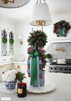 a kitchen decorated for christmas with wreaths and potted plants