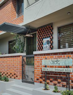 a brick building with an iron gate and sign on it's front entrance area