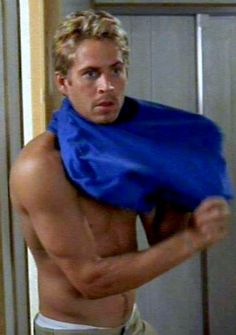 a shirtless man with no shirt on holding a blue scarf over his shoulder and looking at the camera