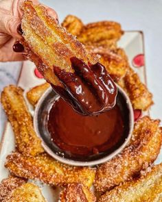 a person dipping some kind of sauce on top of churros in a bowl