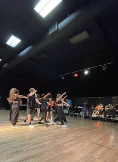 a group of people standing on top of a wooden floor in front of a stage