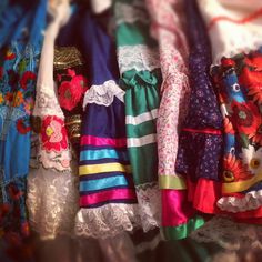 many different colored dresses are hanging on a rack with laces and ribbons around them