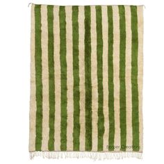 a green and white striped rug with fringes on the bottom, in front of a white background