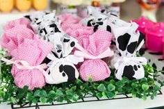 some pink and black stuffed animals are in the middle of green plants on a table