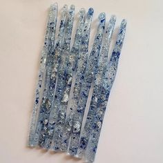 six blue and white toothbrushes sitting on top of each other in front of a white wall