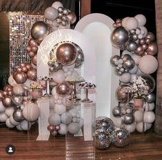 a bunch of balloons that are in front of a wall with silver and white decorations