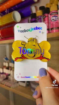 a person holding up a yellow sticker with the word tommy on it in front of some crafting supplies