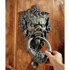 a door handle with a face on it and a hand holding an open ring in front of the door