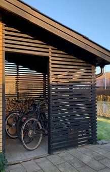 two bikes are parked in front of a wooden structure with slats on the sides