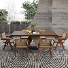 a dining table with chairs around it in front of a concrete wall and planters