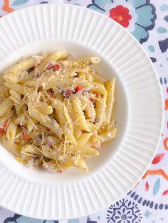 a white plate topped with pasta covered in cheese