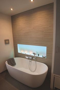 a large white bath tub sitting in a bathroom next to a wall mounted shower head