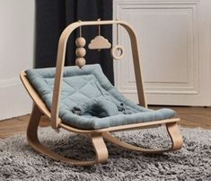 a wooden rocking chair with a blue cushion on it's back in front of a window