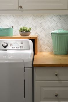 a white washer sitting next to a green pot on top of a wooden counter