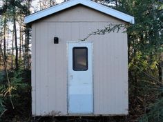 an outhouse in the woods with a door and window