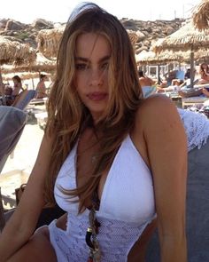 a woman in a white bathing suit sitting on the beach