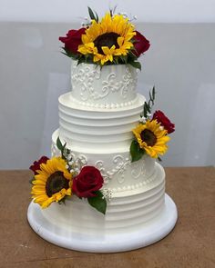 a wedding cake with sunflowers and roses on top