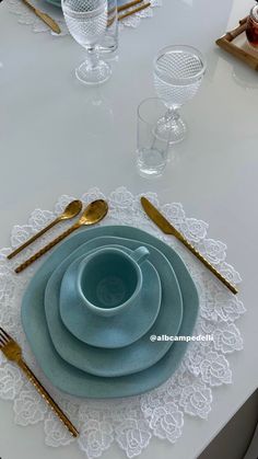 a white table topped with blue plates and silverware on top of a doily