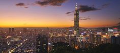 the cityscape is lit up at night with bright lights in the sky and clouds