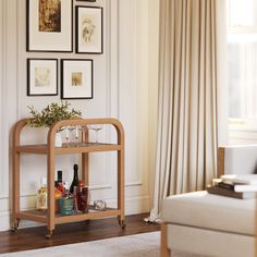 a living room filled with furniture and framed pictures on the wall behind a bar cart