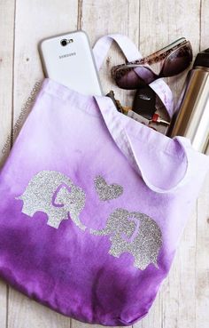 an elephant tote bag sitting on top of a wooden table next to sunglasses and cell phone