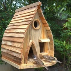 two birds sitting on top of a wooden bird house that is made out of wood