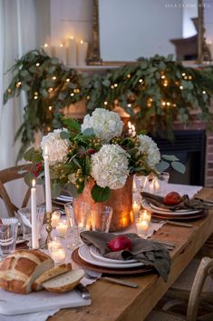 the table is set with candles, flowers and bread for christmas dinner or brunch