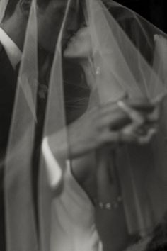 a bride and groom are kissing under the veil