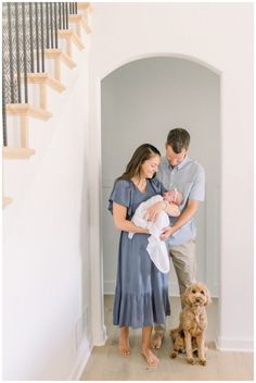 a man and woman holding a baby while standing next to a dog