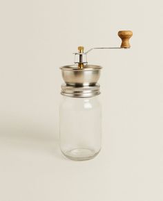 a small glass jar with a metal lid and wooden spigot attached to it