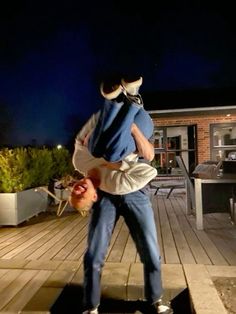 a man holding a baby in his arms while standing on a wooden deck at night