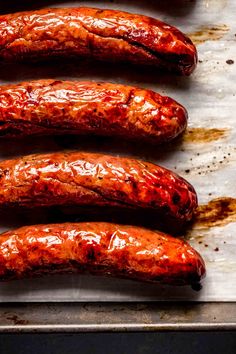 four sausages are lined up on a baking sheet