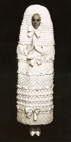 a woman in a white crocheted dress with a bow on her head and legs