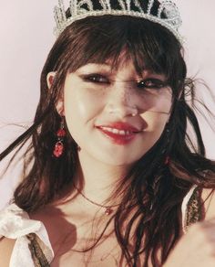 a woman wearing a tiara and smiling at the camera with her hair blowing in the wind