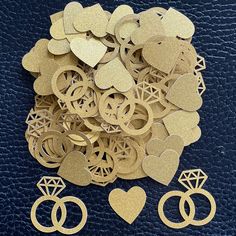 a pile of gold wedding rings and diamond cutouts on top of a blue leather background