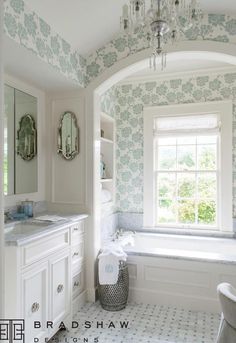 a bathroom with blue and white wallpaper, sink, mirror and tub in it