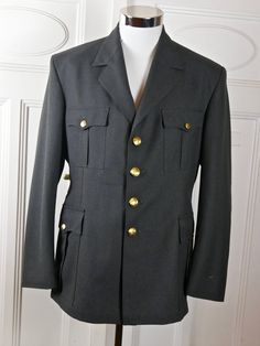 "This military jacket is in near mint condition and is a prime example of exquisite vintage Norwegian military tailoring. The European officer blazer is gunmetal gray, has a notch collar, and closes in the front with two gold buttons. The buttons have an upright crowned lion on them, as do the pockets on the four pockets on the front of the jacket (2 flap pockets at hip level and two on the chest). The NATO jacket has a center back vent that allow complete ease of movement. The jacket is fully l Formal Military Outerwear With Button Closure, Military Style Formal Outerwear With Pockets, Military Style Formal Blazer With Buttons, Military Style Blazer With Buttons For Formal Occasions, Military Uniforms Long Sleeve Formal, Military Style Long Sleeve Formal Uniforms, Military Uniform Style Blazer For Fall, Formal Military Uniform With Long Sleeves, Uniform Style Military Blazer For Fall