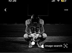 a black and white photo of a football player sitting on the field with his hands in his pockets