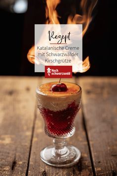 a dessert in a glass on top of a wooden table with flames coming out of it