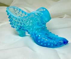 This vintage Fenton hobnail glass shoe figurine features a cat head design in light blue opalescent glass. The intricate detailing and unique design make it a perfect addition to any decorative glassware collection. The shoe is a reproduction of a Victorian style slipper, and is perfect for those who appreciate vintage art glass. The hobnail pattern, color, and material of this decorative shoe make it a great gift for glass collectors and enthusiasts. It would make a great addition to any home decor, whether displayed on a shelf or used as a unique paperweight. This Fenton figurine is a vintage original and is sure to be a conversation starter. Some wear. Glass Shoe, Fenton Hobnail, Glass Shoes, Vintage Art Glass, Glassware Collection, Head Design, Decorated Shoes, Slipper Shoes, Victorian Style