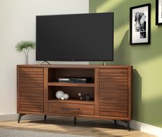 a flat screen tv sitting on top of a wooden entertainment center next to a green wall