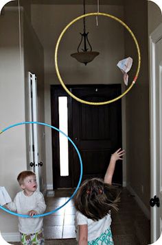 two children playing with hoop toys in the hallway